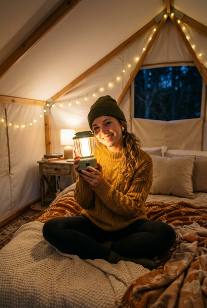 Woman in glamping tent holding LunaGlow lantern with warm golden light on face